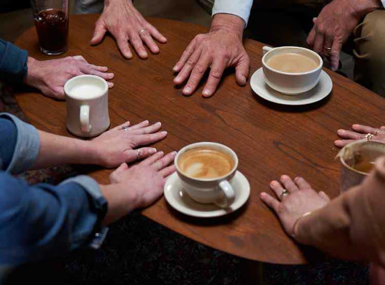 A group of people with their hands flat on a coffee table